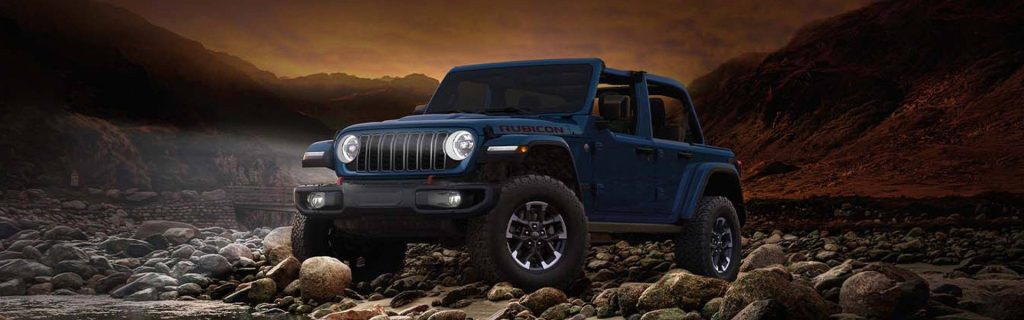 Jeep Wrangler on rocky terrain at sunset.
