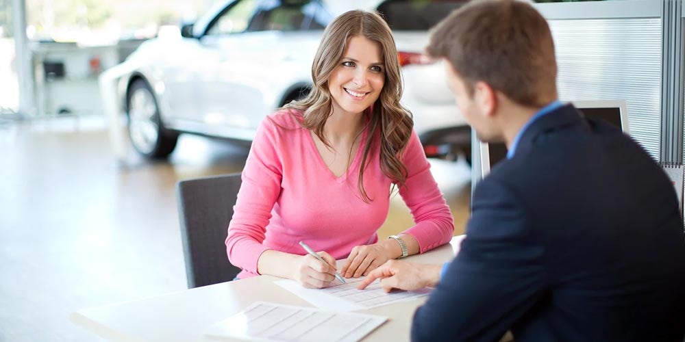 Car shopper sitting down with employee at dealership